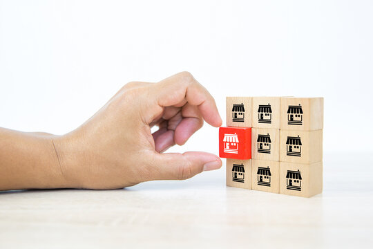Franchise, Close-up hand choose cube wooden toy block stacked with franchises business store icon for business growth and branch expansion and bank loan.