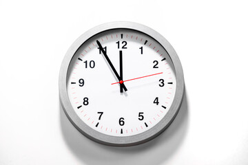 It is five to twelve, the clock is ticking. Grey Watch shows the time 5 before 12. Close up to a wall clock, with five minutes to twelve o'clock. Time is running out. White background with copy space