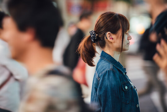 補聴器をつけた若い女性が人混みの中で耳を澄ませ音を聞いている