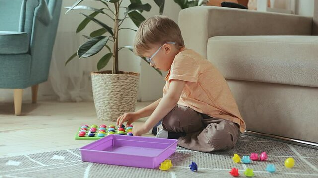 Child playing with Educational Game Toy sitting on the floor at home. Develops fine motor skills