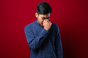 Young handsome asian man wearing casual shirt standing with hand on head for pain in head because stress. Suffering migraine.