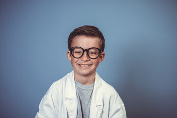 cool school boy with thick black glasses is dressed as mad scientist with white coat in front of blue background