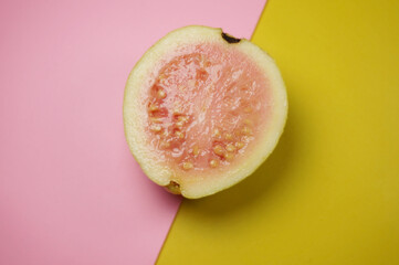 Guava fruit on pink and yellow background with selective focus.