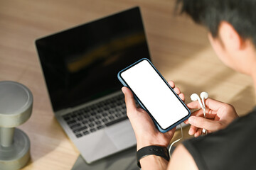 Close up view of man using smart phone during exercising in living room.
