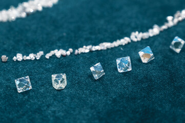 Several large diamonds lie on the turquoise velvet. Close-up photo. Cut diamond