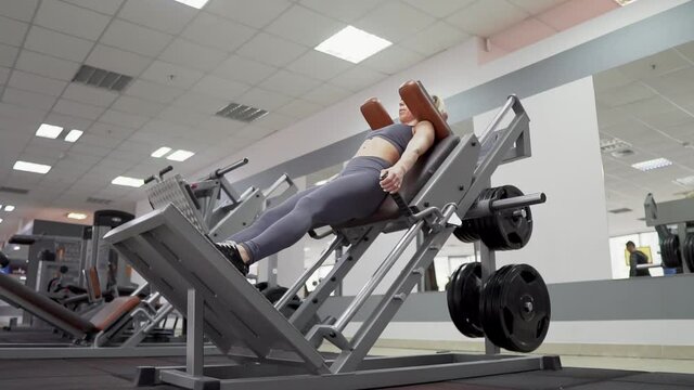Fit woman practicing back squats in exercise machine