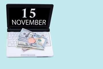 Fototapeta na wymiar Laptop with the date of 15 november and cryptocurrency Bitcoin, dollars on a blue background. Buy or sell cryptocurrency. Stock market concept.