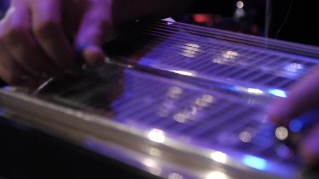 Close up of a musician playing lap steel, pedal guitar, slide guitar on stage.
