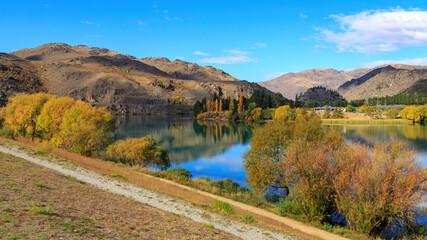 Autumn in Cromwell, a town in the South Island of New Zealand. Mountains and trees with colorful foliage surround Lake Dunstan