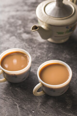 Indian chai in glass cups with metal kettle and other masalas to make the tea.