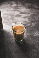 Indian chai in glass cups with metal kettle and other masalas to make the tea.