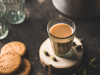 Indian chai in glass cups with metal kettle and other masalas to make the tea.