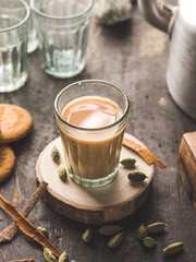 Indian chai in glass cups with metal kettle and other masalas to make the tea.