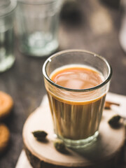 Indian chai in glass cups with metal kettle and other masalas to make the tea.