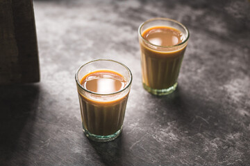 Indian chai in glass cups with metal kettle and other masalas to make the tea.