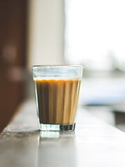 Indian chai in glass cups with metal kettle and other masalas to make the tea.