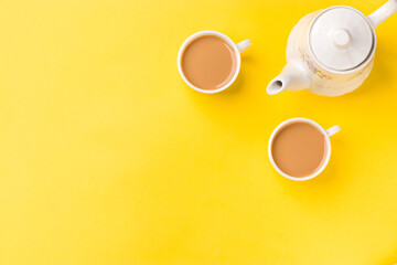 Fototapeta na wymiar Milk tea on white cup with white kettle on yellow background stock image.