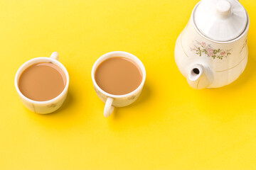 Obraz na płótnie Canvas Milk tea on white cup with white kettle on yellow background stock image.