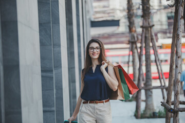 Fototapeta premium Young woman with shopping bags. Happy woman with shopping bags enjoying in shopping. lifestyle concept. Fashion woman with shopping bags walking on street.