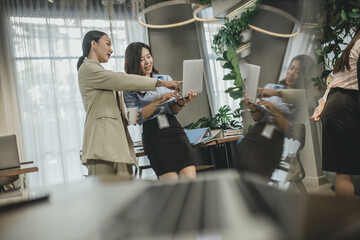 Young Asain businesswoman working together in office. Two women with laptop in open space office. Business concept. Business project team working together at meeting room at office