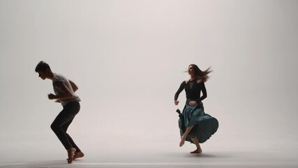 Elements of modern choreography, contemporary performed by a young couple of dancers on a white studio background. Man and woman dance passionately, expressing their feelings in a dance. Slow motion. - Powered by Adobe