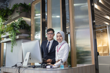 young Asian reception team hotel front desk welcoming . Asian reception welcoming the customer into hotel front desk counter for service the customer,
