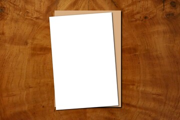 Blank white paper sheet on brown envelope on wooden background in top view Mock up
