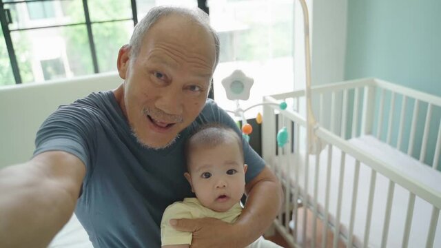 Cheerful Asian Grandparent and Little Cute baby boy smiling taking selfie photos with smartphone