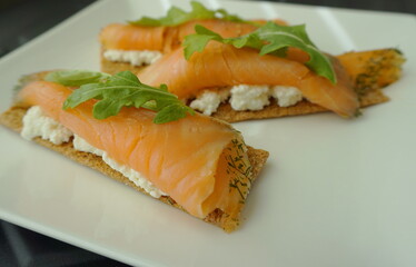Healthy breakfast idea. Crisp with ricotta cheese, salmon and arugula on the top.