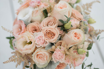 Close up of beautiful bridal bouquet of white flowers and greenery, decorated with long silk ribbon lies on white background. Copy space
