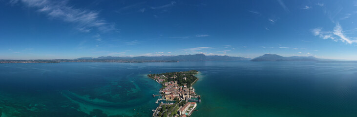 Fototapeta na wymiar Panorama of Lake Garda. Aerial view of the island of Sirmione. Sirmione, Lake Garda, Italy. Peninsula on a mountain lake in the background of the alps. Castle on the water in Italy.