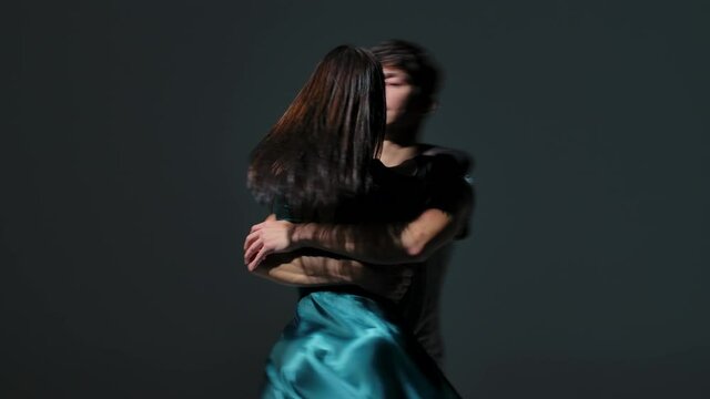 Sensual contemporary dance performed by a romantic couple of dancers. Young man and woman dancing passionately, hug and touch each other tenderly on gray studio background. Close up. Slow motion.