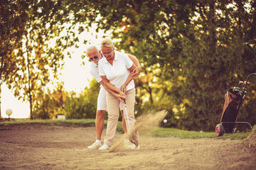 Man teaching woman to play golf.