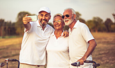 Senior golfers using phone and taking self portrait.