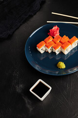 rolls in caviar on a blue plate on a black textured background