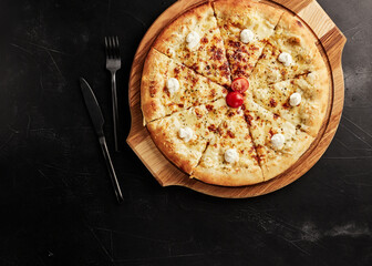 pizza on a wooden base on a black textured background top view