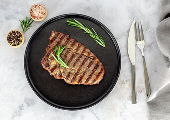 Traditional entrecote, cut from the rib. Medium rib eye steak on the plate with cutlery and seasonings.