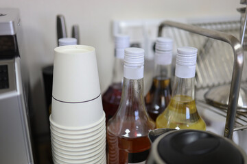 Bottles of syrup on the coffee table. Paper cups. Blurred background.