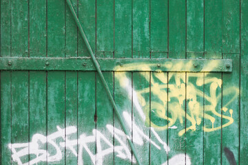  Inscriptions on the green fence. Texture of old painted wood. Multi-layer old paint. Cracks in the paint. Graffiti.