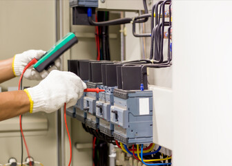 Electrical engineer tests the operation of the electric control cabinet on a regular basis for maintenance.