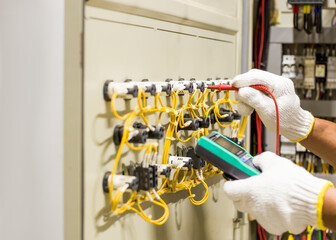 Electrical engineer tests the operation of the electric control cabinet on a regular basis for...