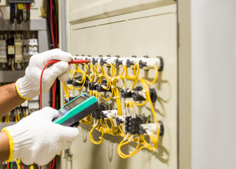 Electrical engineer tests the operation of the electric control cabinet on a regular basis for maintenance.