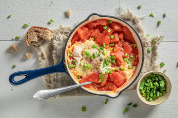 Naklejka premium Hot shakshuka with tomatoes and eggs. Tunisian cuisine for breakfast.