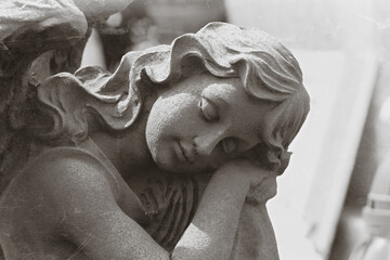Grave detail, black and white image of sleeping angel sculpture, copy space for text, death and...