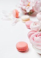 close-up view of pink and white macaroons, beautiful tender roses on a light background with copy space, selective focus 