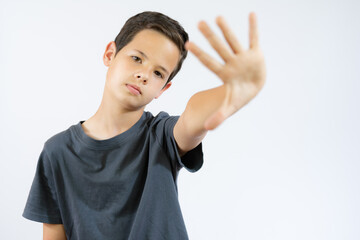 portrait of young boy doing stop symbol over white background