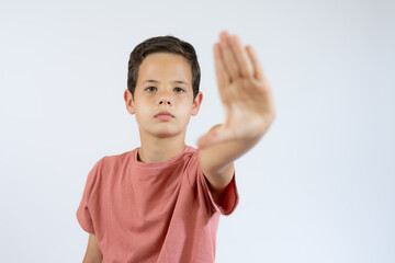 portrait of young boy doing stop symbol over white background