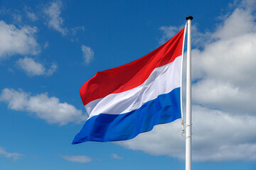 Fototapeta na wymiar National flag of the Netherlands with horizontal tricolour of red, white and blue, Dutch flag waving on the air in a sunny day and blue sky background.