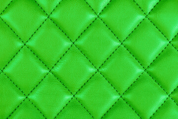 Modern luxury car green leather interior. Part of perforated leather car seat details. Green perforated leather texture background. Texture, artificial leather with diagonal stitching. Leather seats