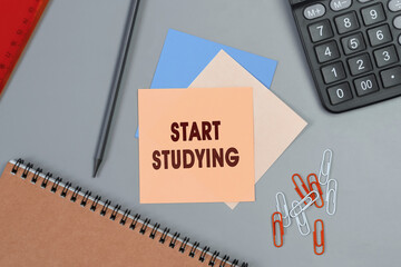 Start Studying - concept of text on sticky note. Closeup of a personal agenda. Top view. Office concept